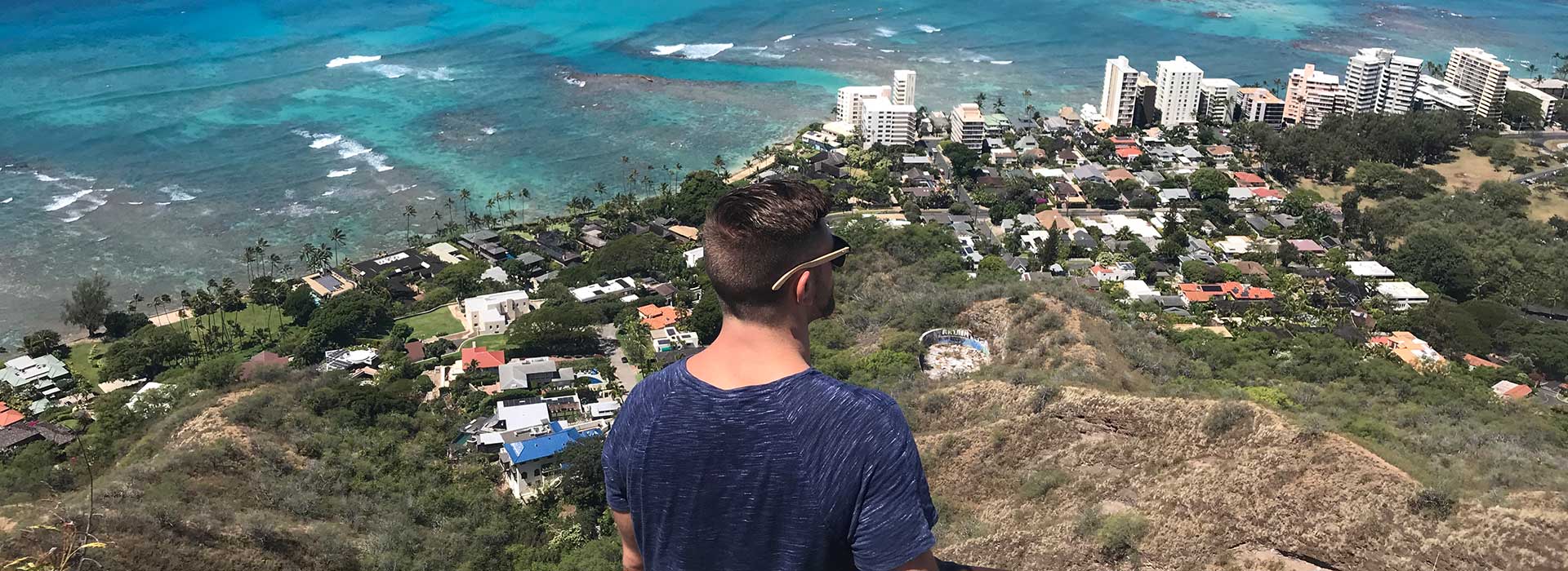 Man on mountain looking out over oceanside community